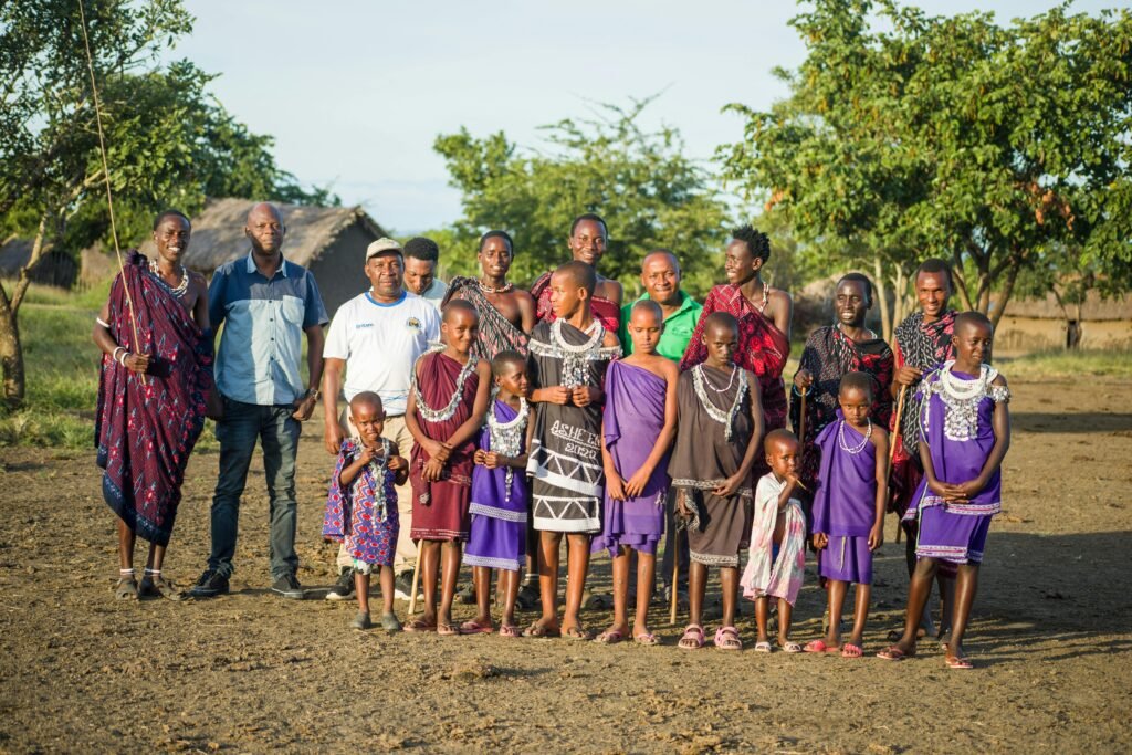 A diverse group of Tanzanian people in traditional attire outdoors, showcasing cultural heritage.